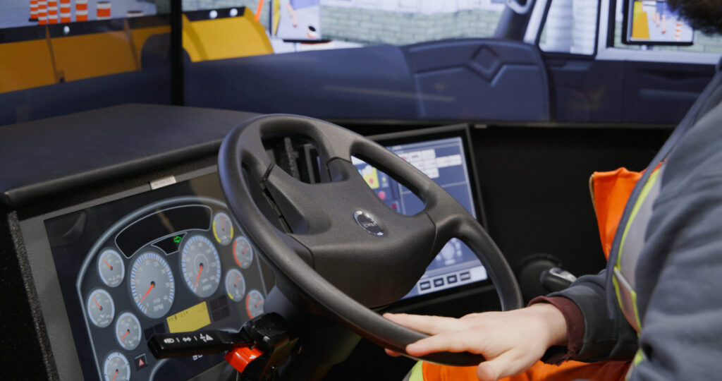 Close up of a man steering a snowplow simulator